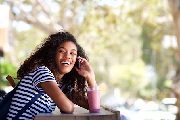 Belle jeune femme noire souriant et parlant au téléphone portable