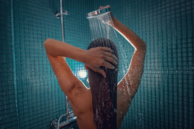 Belle jeune femme nue prenant une douche dans la salle de bain, il est heureux et détendu.