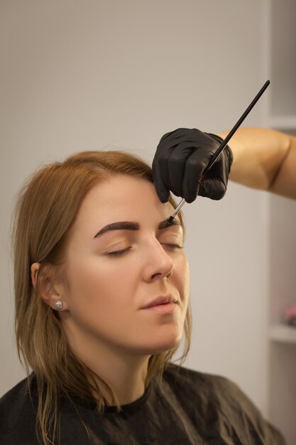 Photo belle jeune femme obtient une procédure de correction des sourcilsjeune femme peignant ses sourcils dans un salon de beauté