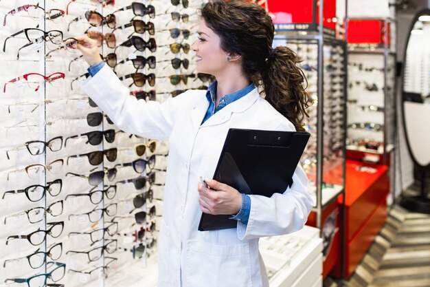 Belle jeune femme ophtalmologiste debout dans un magasin d'optique.