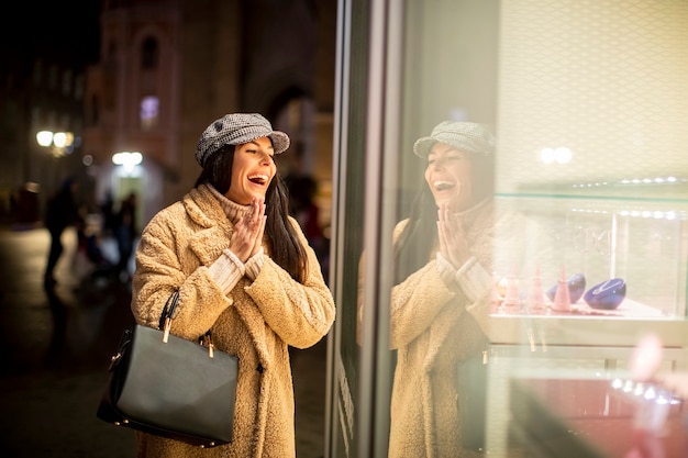 Belle jeune femme par la vitrine au moment de Noël