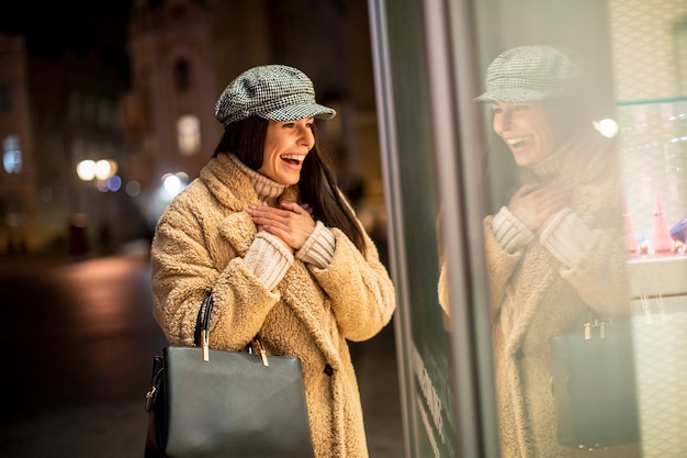 Belle jeune femme par la vitrine au moment de Noël