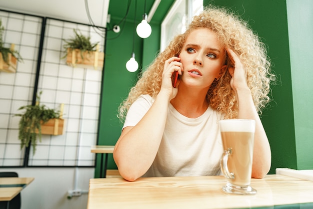 Belle jeune femme parlant au téléphone au café