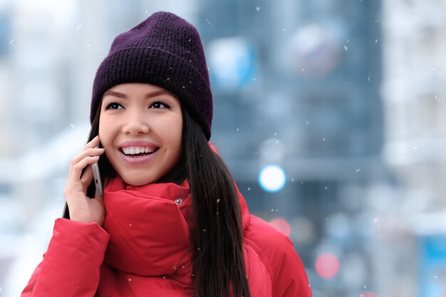 Belle jeune femme parlant au téléphone portable à l'extérieur le jour de l'hiver