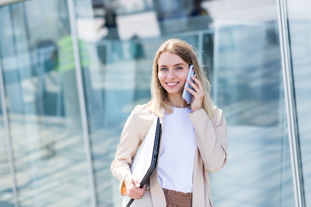 Belle jeune femme parlant sur un téléphone portable près du bureau, une femme d'affaires en pause déjeuner