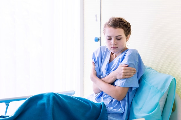 Belle jeune femme patiente avec de la fièvre et épuisée dans une chambre d&#39;hôpital.