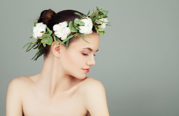 Belle jeune femme à la peau claire et saine, feuilles vertes et couronne de fleurs de coton blanc Profil féminin parfait