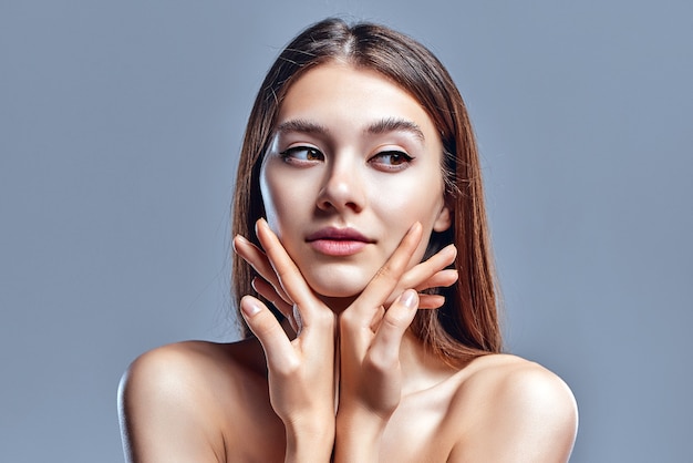 Belle jeune femme avec une peau parfaite et propre. Portrait de modèle de beauté avec maquillage nude naturel. Spa, soins de la peau et bien-être. Gros plan, fond gris, fond.