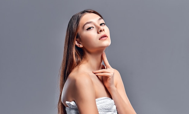 Belle jeune femme avec une peau parfaite et propre. Portrait de modèle de beauté avec maquillage nude naturel. Spa, soins de la peau et bien-être. Gros plan, fond gris, fond.