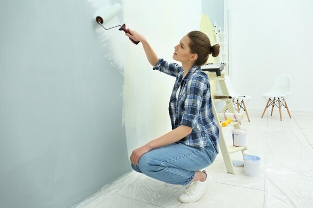 Belle jeune femme peignant le mur dans la chambre