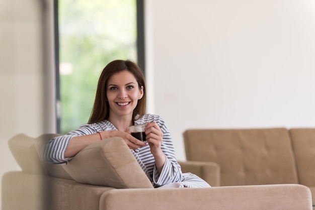 Belle jeune femme en peignoir profitant du café du matin dans sa luxueuse villa