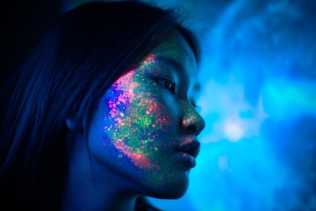 Une belle jeune femme avec la peinture sur le visage qui détourne le regard.