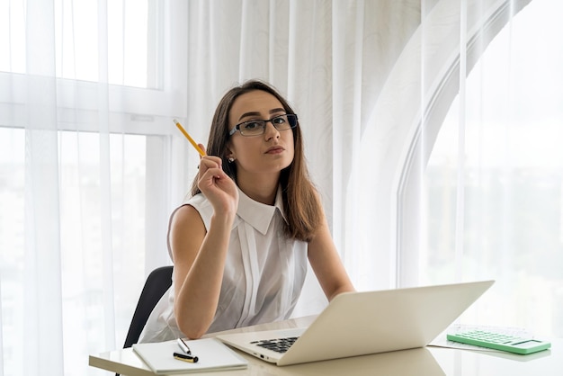 Belle et jeune femme avec la pensée d'ordinateur portable