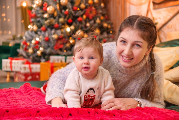 belle jeune femme avec petit enfant près de l'arbre de noël à noël