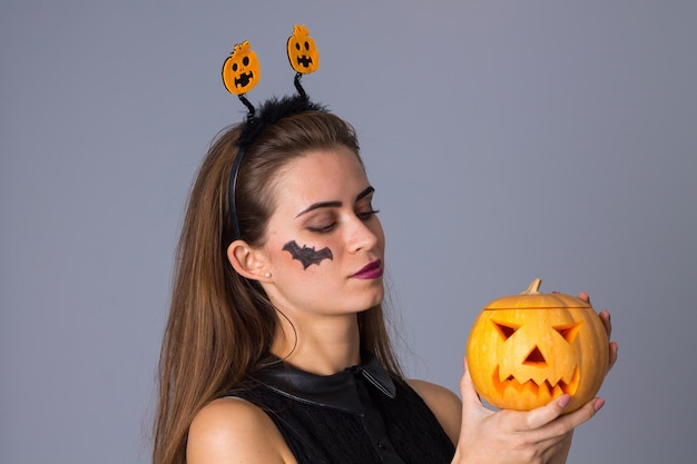 Belle jeune femme avec une petite photo de chauve-souris sur sa joue et un bandeau avec des citrouilles