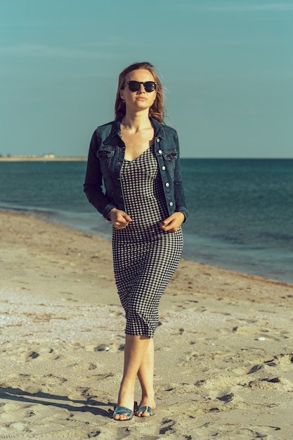 Belle jeune femme sur la plage de l'océan au coucher du soleil