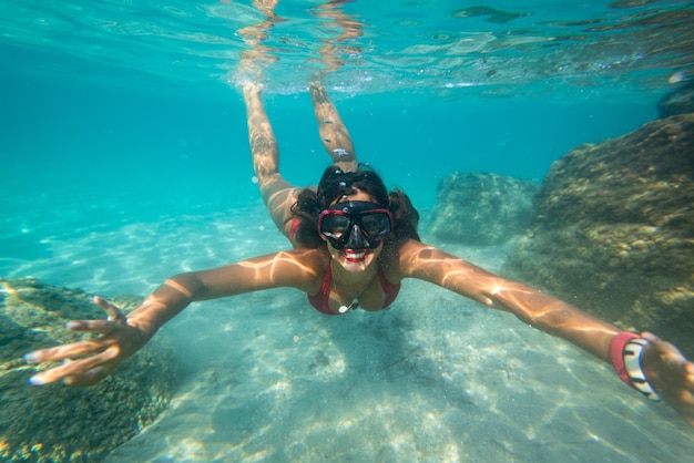 Belle jeune femme plongée avec masque sous l'eau dans la mer.