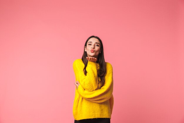 Belle jeune femme portant un chandail chaud debout isolé sur rose, posant