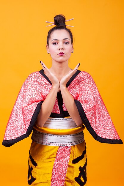 Photo belle jeune femme portant un costume japonais sur fond jaune