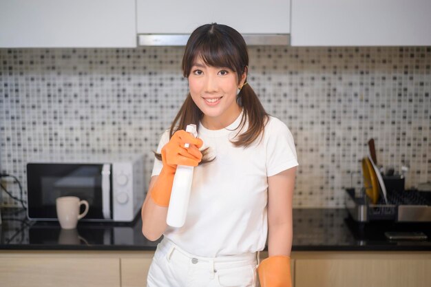 Une belle jeune femme portant des gants de protection en caoutchouc nettoie la table dans la cuisine à la maison.