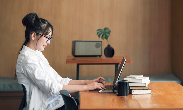 Belle jeune femme portant des lunettes travaillant avec une tablette dans le salon à la maison.