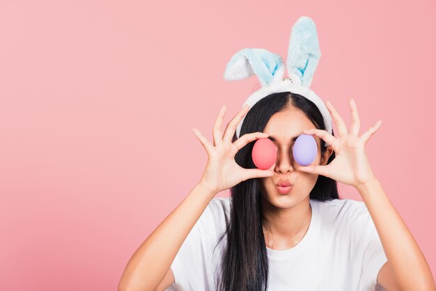 Belle jeune femme portant des oreilles de lapin tenant les yeux avant des oeufs de Pâques colorés