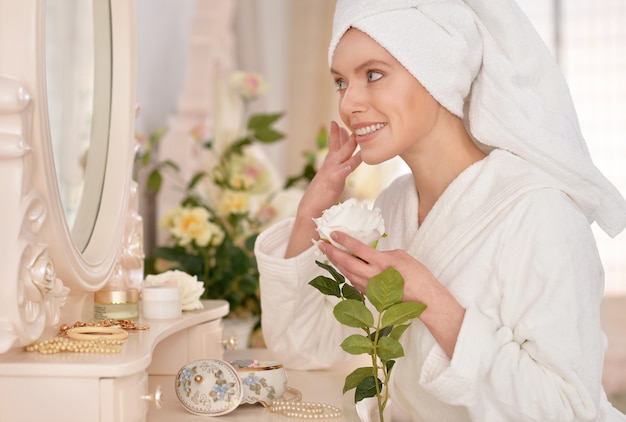 Belle jeune femme portant un peignoir blanc près du miroir