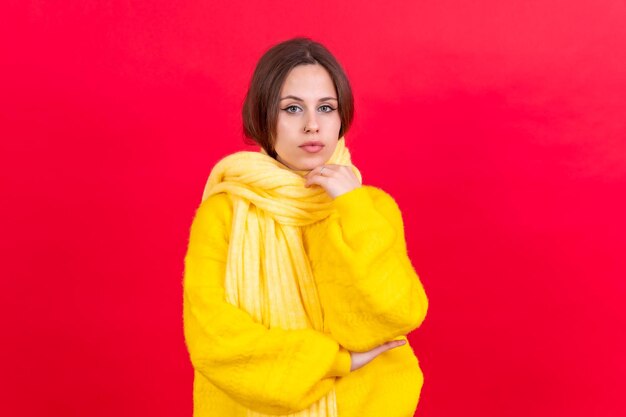 Belle jeune femme portant un pull en laine jaune chaud sur fond rouge espace pour le texte