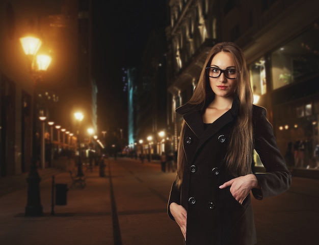 Belle jeune femme porte des lunettes contre une ville de nuit