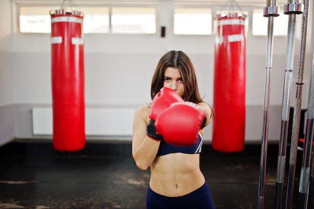Belle jeune femme, porter des gants de boxe pour faire des exercices et travailler dur dans une salle de sport