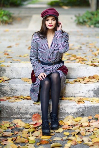 Belle jeune femme, porter, manteau hiver, et, cap, reposer étapes, de, automne, feuilles