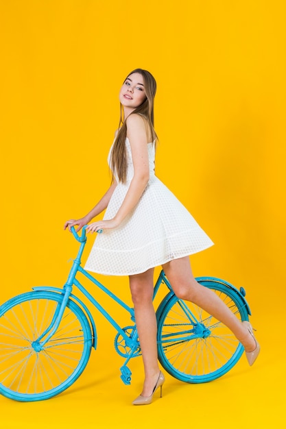 Belle jeune femme posant assise sur un vélo bleu