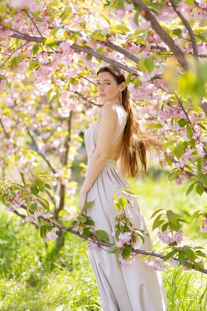 Belle jeune femme posant dans un jardin fleuri de sakura.