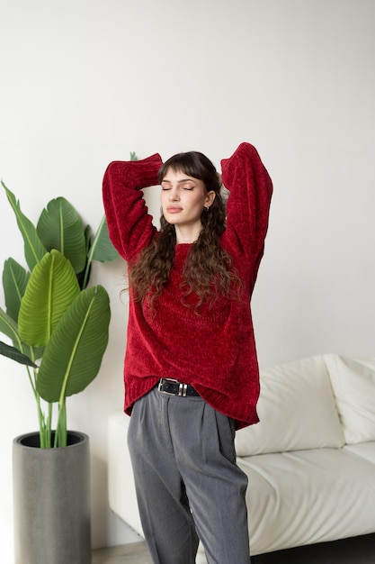 une belle jeune femme posant dans un pull rouge en studio