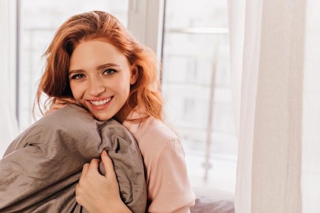 Belle jeune femme posant dans son lit Portrait intérieur d'une fille gracieuse au gingembre appréciant le matin