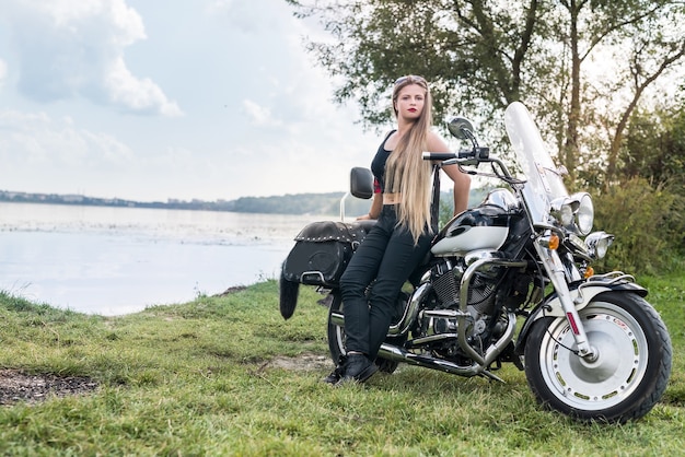 Belle jeune femme posant avec moto à l'extérieur