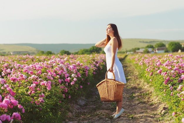 Belle jeune femme posant près de roses dans un jardin.