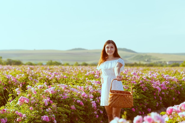 Belle jeune femme posant près de roses dans un jardin.