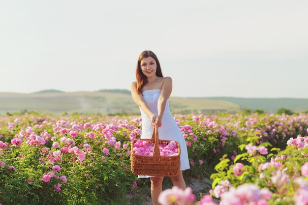 Belle jeune femme posant près de roses dans un jardin.