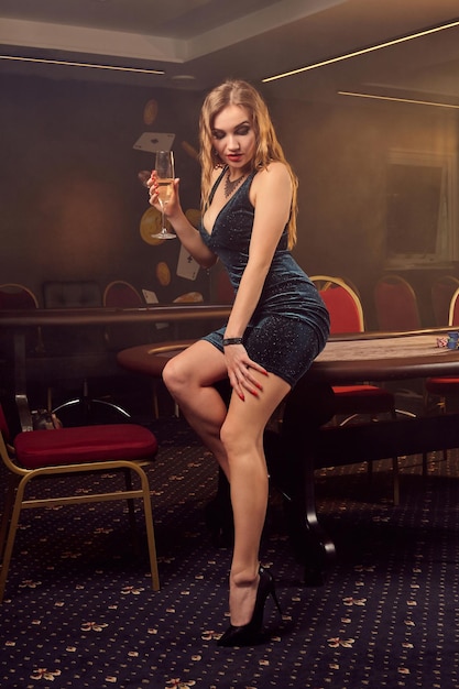 Une belle jeune femme pose assise sur une table de poker dans un casino de luxe.
