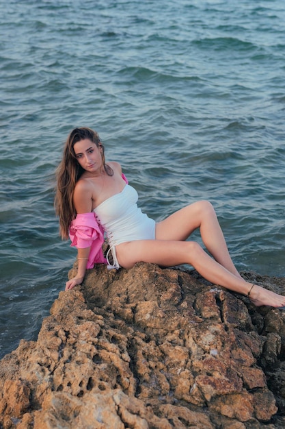 Belle jeune femme pose avec la mer en arrière-plan au coucher du soleil