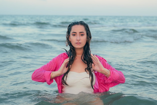 Belle jeune femme pose avec la mer en arrière-plan au coucher du soleil