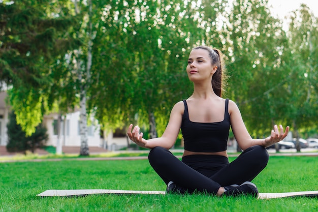 Belle jeune femme pratiquant le yoga dans le parc