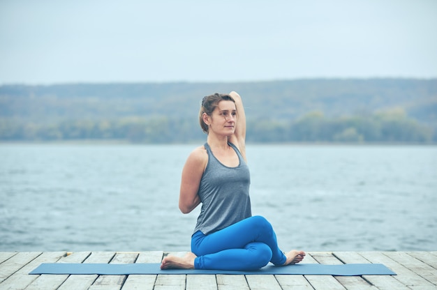 Belle jeune femme pratique le yoga asana Gomukhasana