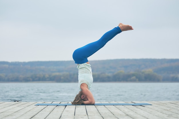 Belle jeune femme pratique le yoga asana Shirshasana