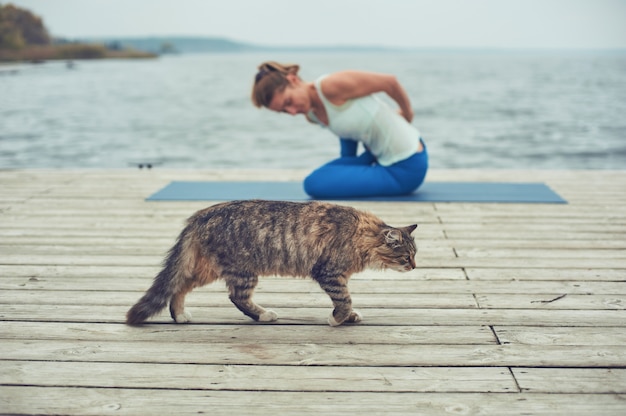 Belle jeune femme pratique le yoga asana sur la terrasse en bois près du lac