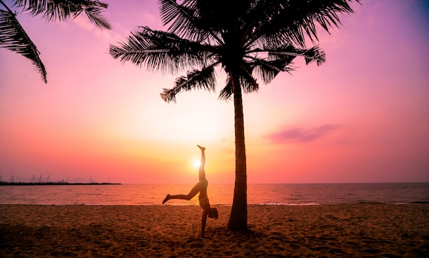 Belle jeune femme pratique le yoga à la plage. Exercice tôt le matin. lever du soleil