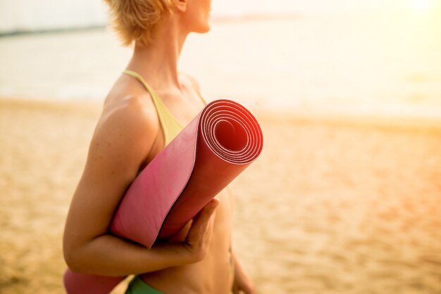 Belle jeune femme pratique le yoga à la plage. Exercice tôt le matin