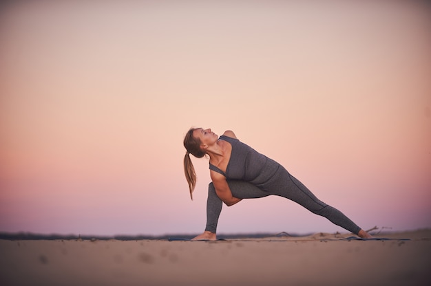 Belle jeune femme pratique le yoga twist asana Parivritta Parshvakonasana