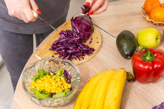 Belle jeune femme prépare une salade de légumes dans la cuisine. Cuisiner à la maison.